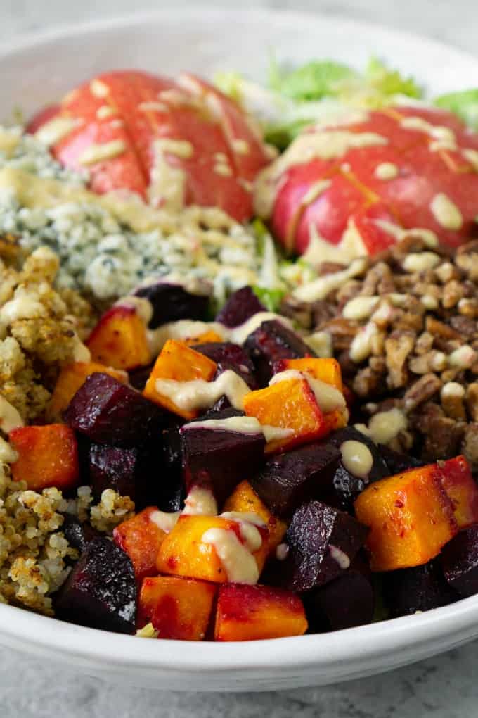 A fall harvest salad that celebrates all things fall. Loaded with brussels sprouts, blue cheese, crispy quinoa, roasted beets, and butternut squash and topped with the most delicious champagne apple cider vinaigrette! #fallsalad #harvest #applevinaigrette close up of fall harvest salad