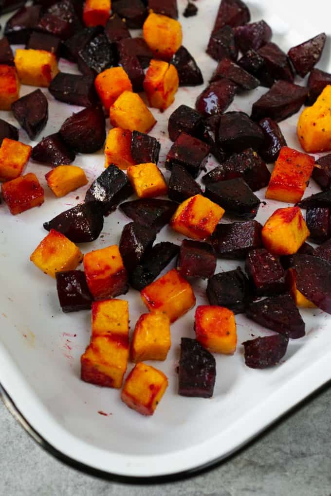 A fall harvest salad that celebrates all things fall. Loaded with brussels sprouts, blue cheese, crispy quinoa, roasted beets, and butternut squash and topped with the most delicious champagne apple cider vinaigrette! #fallsalad #harvest #applevinaigrette roasted beets and butternut squash in a white baking dish