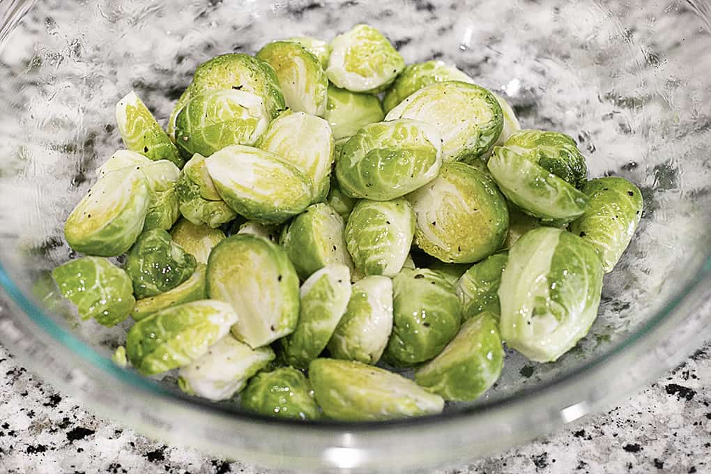 This Roasted Brussels Sprout Recipe with Parmesan is an easy side dish that will be perfect with so many meals!! #Brusselssprouts #sidedish #Parmesan Bowl of Brussels Sprouts with Olive Oil and Seasoning