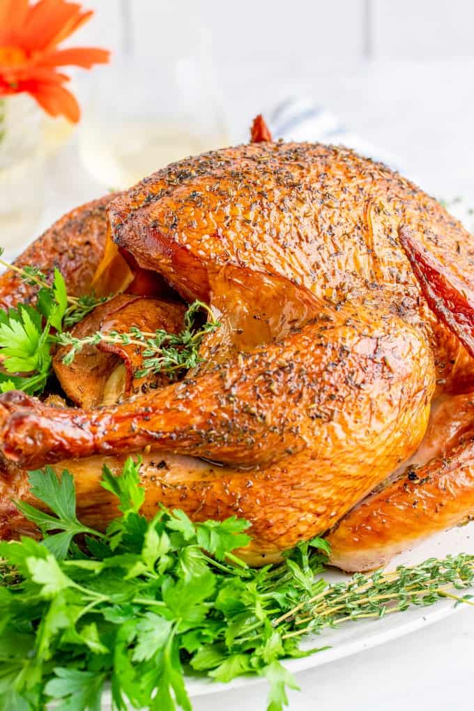 The Quintessential Guide for Smoking a Turkey will help you through brining, smoking and the best gravy ever! You won't find a better turkey than this. Smoked Turkey on a platter with fresh herbs.