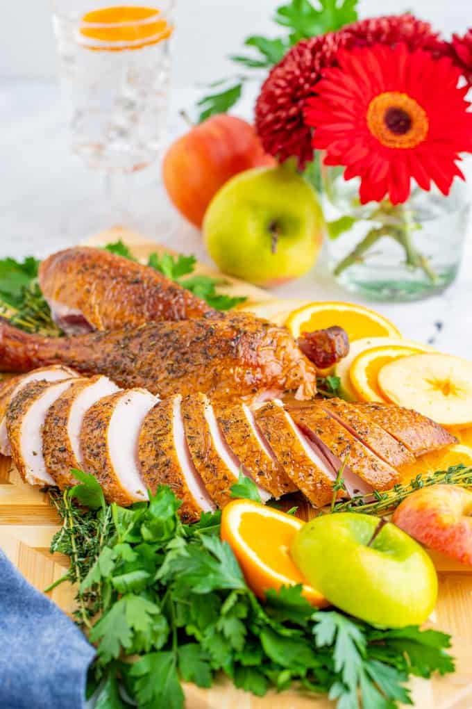 The Quintessential Guide for Smoking a Turkey will help you through brining, smoking and the best gravy ever! You won't find a better turkey than this. Sliced turkey on a board with sliced apples and oranges and herbs