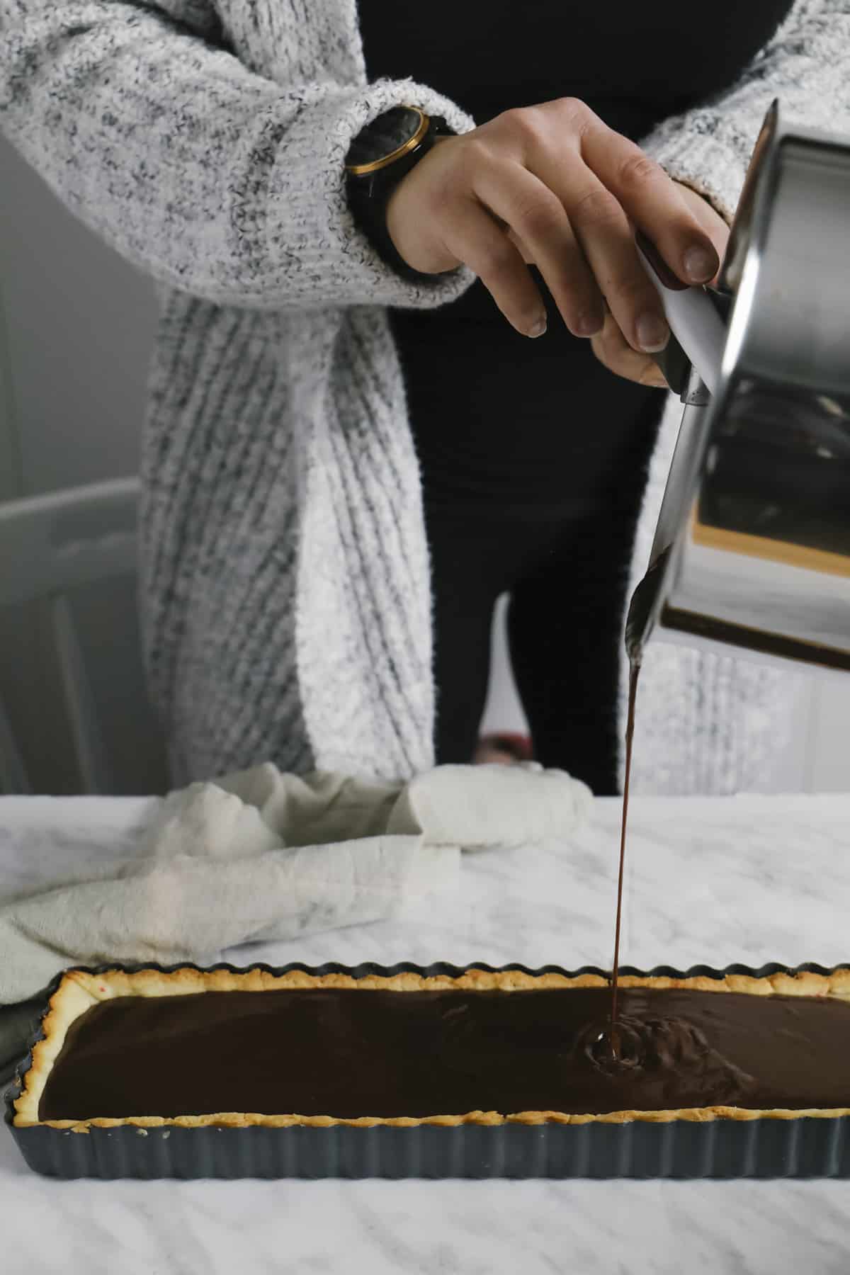 This delicious, decadent chocolate tart is a perfectly balanced recipe with a rich chocolate ganache and a raspberry jam on a buttery crust. Pouring chocolate filling into a rectangle tart shell
