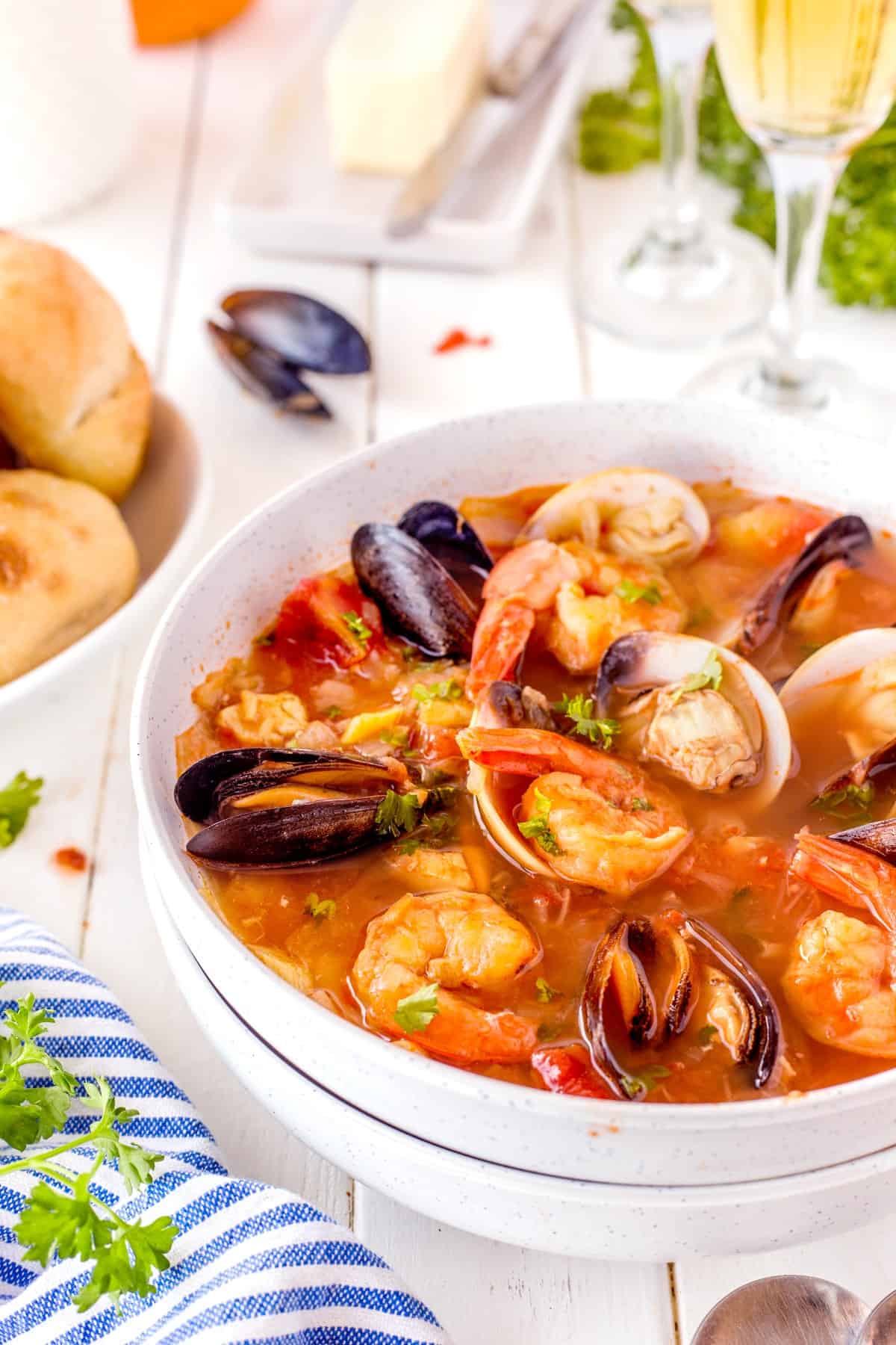 Cioppino (Fisherman's stew) is filled with shrimp, clams, mussels, white fish, and snow crab claws and simmered in a rich broth made from tomato/garlic and fish stock. Vertical picture of a bowl of Cioppino
