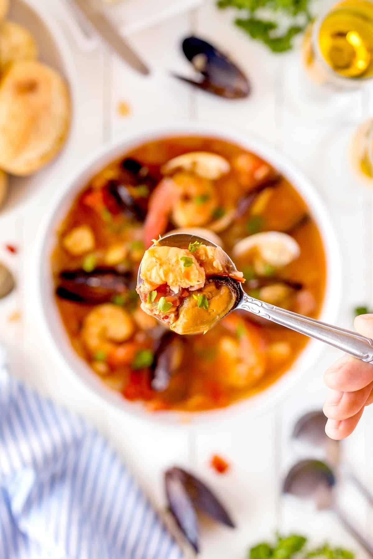 Cioppino (Fisherman's stew) is filled with shrimp, clams, mussels, white fish, and snow crab claws and simmered in a rich broth made from tomato/garlic and fish stock. Spoonful of Cioppino