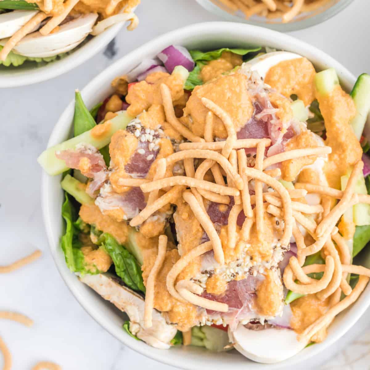 This Ahi Tuna Salad will fill the void for an Asian craving. Gorgeous, slightly seared crusted tuna is on top of a bed of salad with the best Asian dressing around! Finish it off with a little crunch from some chow mein noodles, and you have the perfect salad. Overhead view of Ahi Tuna Salad