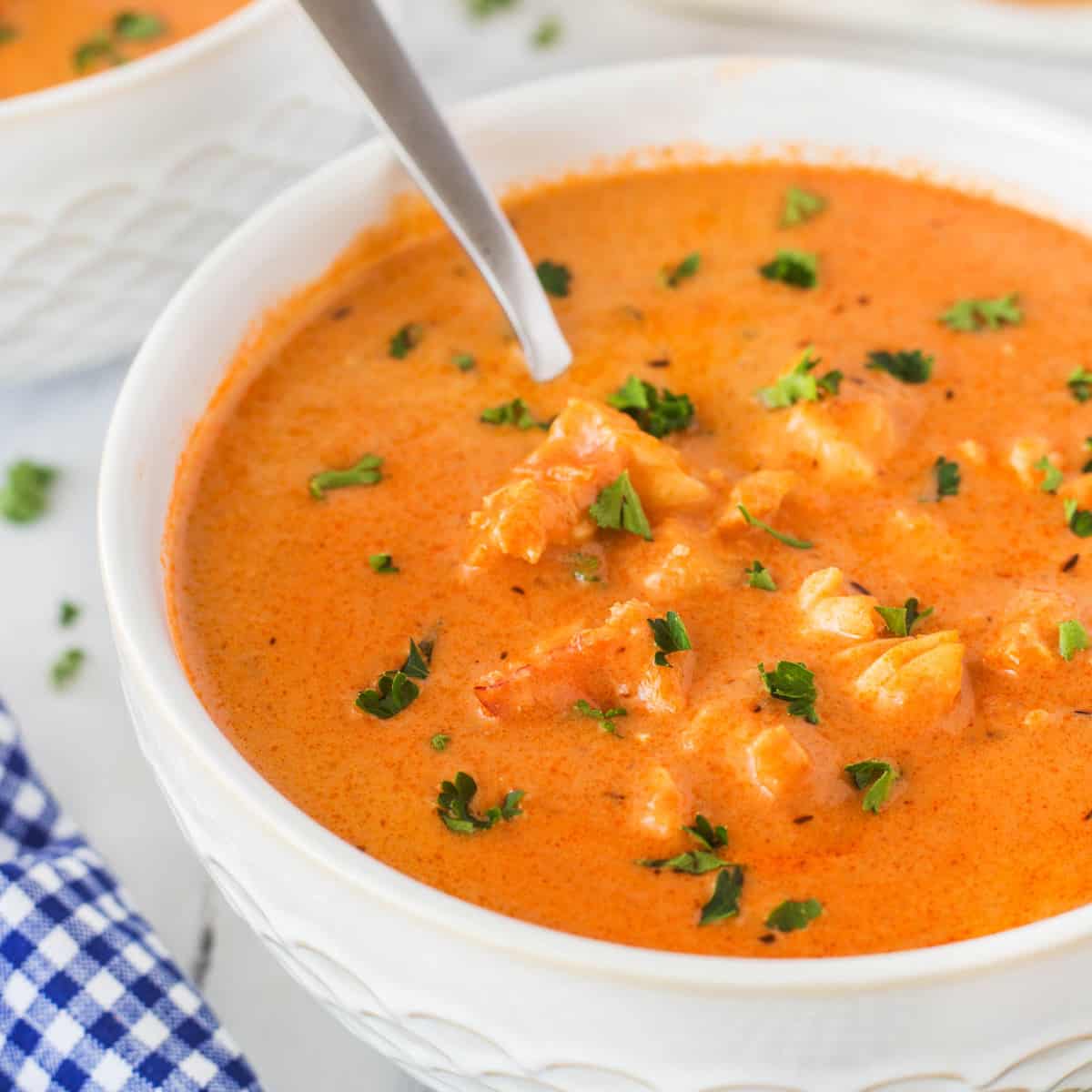 This Best Lobster Bisque Recipe is a tried and true recipe that is bursting with flavor and chunks of wonderful lobster in each bite. Lobster Bisque in a bowl with a spoon dunked in.