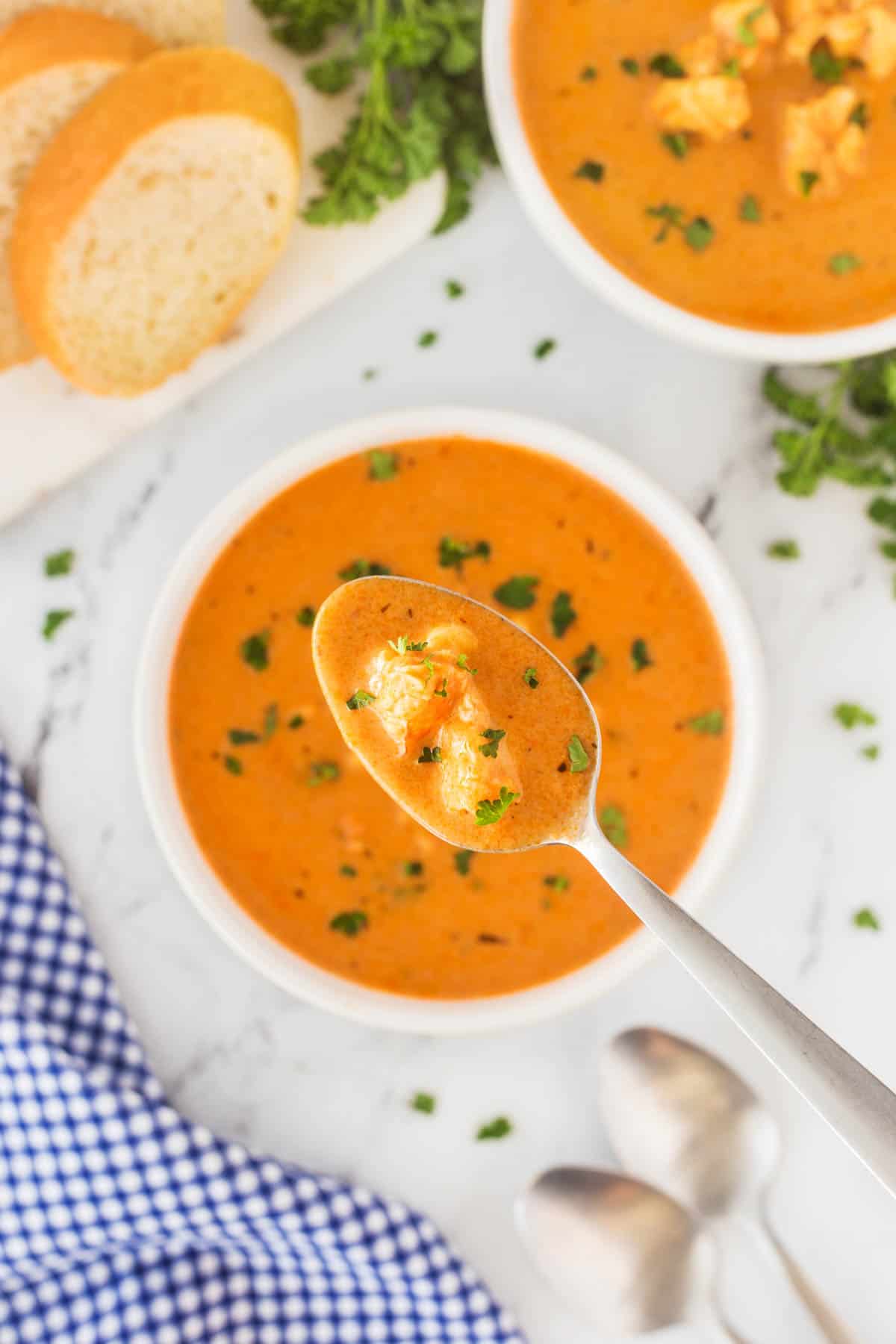 This Best Lobster Bisque Recipe is a tried and true recipe that is bursting with flavor and chunks of wonderful lobster in each bite. Overhead shot of lobster bisque spoonful.