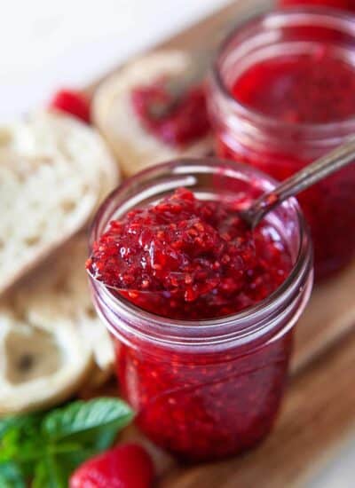 Taking a spoonful of raspberry jam from a jar.