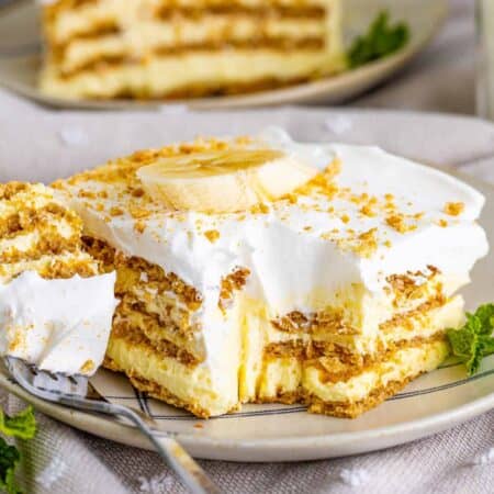 A serving of Banana Icebox Cake on a plate with a forkful on the side.