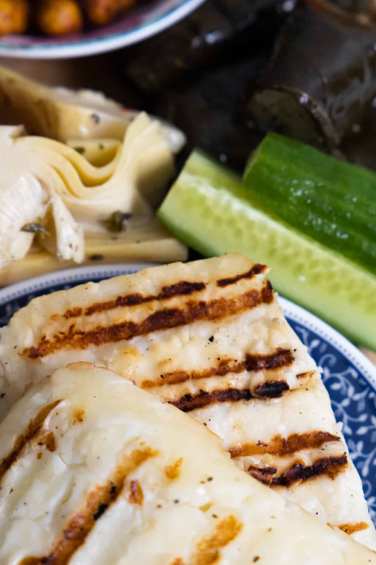 This Mediterranean Mezze Platter is a feast of flavors and perfect for any occasion in place of a charcuterie board. Close up of grilled halloumi with sliced cucumber in the back.