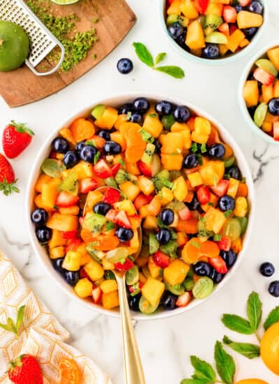 Overhead of a spoon in a bowl of fruit salad.