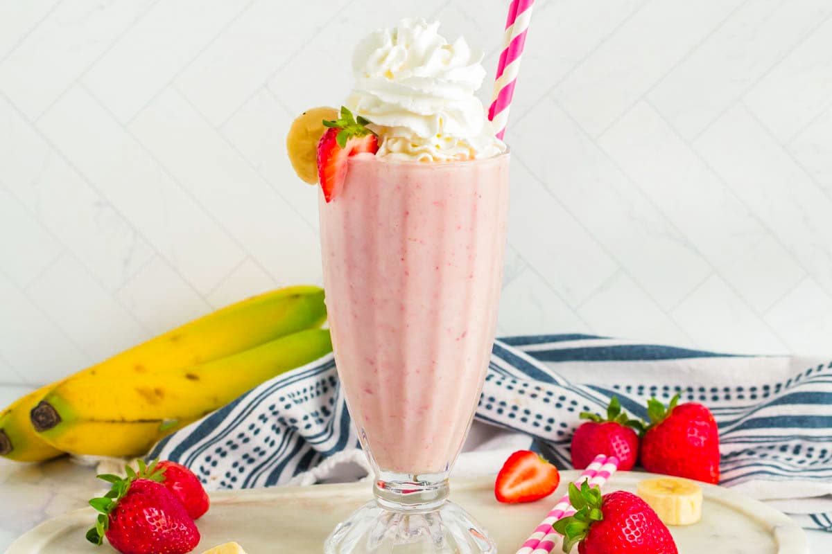 This Strawberry Banana Milkshake will bring back memories of childhood or create new memories for you to enjoy. Rich, creamy and full of fruit, this frozen treat is a delight. Horizontal photo of a strawberry banana milkshake.