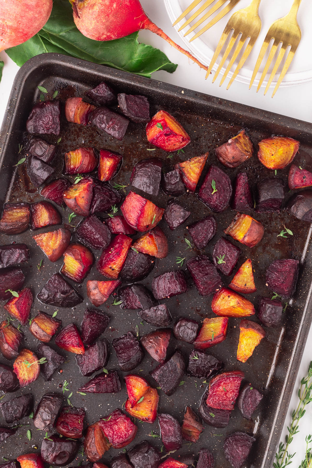 Roasted Beets are an all-time favorite vegetable as they are easy to make and so delicious when cooked on high in the oven. Close-up roasted beets on a dark baking sheet.