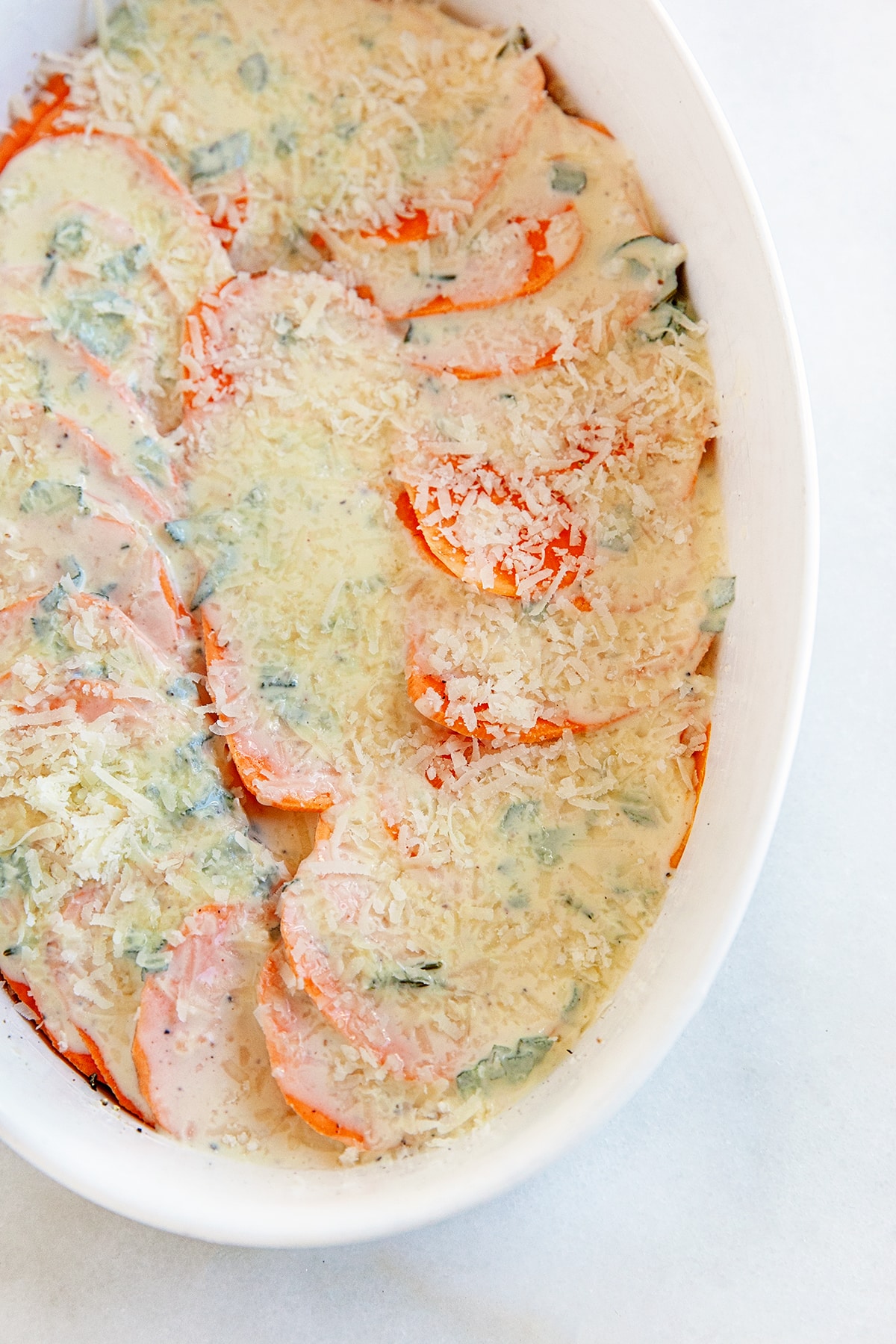 This Sweet Potato Au Gratin will be a hit with family and friends for the holidays. With a creamy herb and cheese flavored sauce and a crunchy savory topping - what is not to love!! Showing the layers of sweet potato casserole with cream and cheese.
