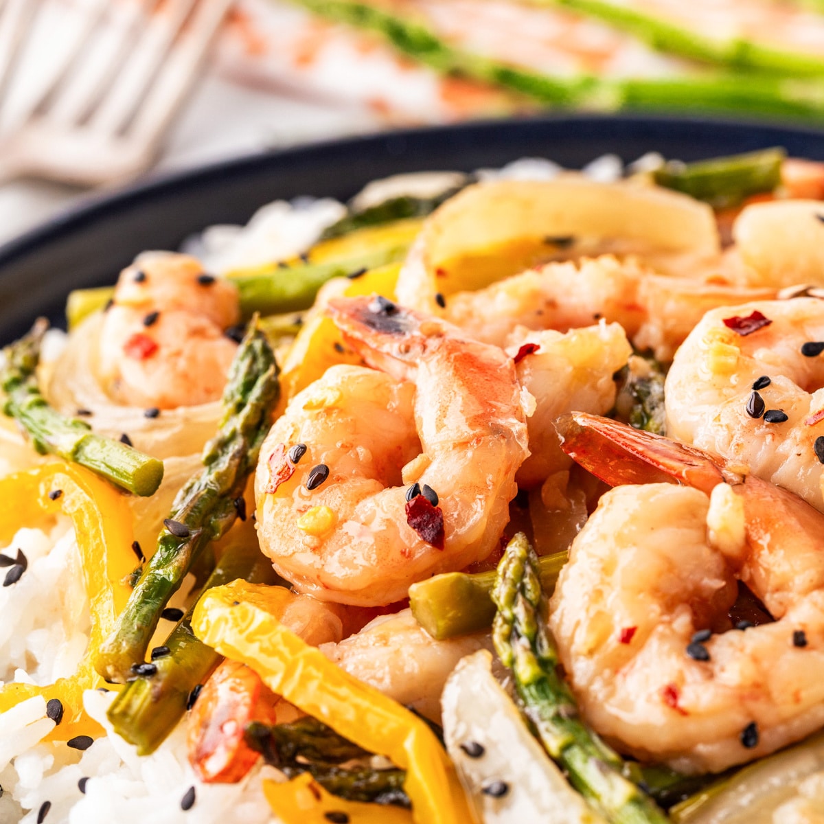 This awesome Shrimp Stir Fry Recipe - Easy Oven Method will have you grabbing the sheet pan again and again. The stir fry sauce with honey, garlic, ginger and more will be what you fall in love with. Square photo of Shrimp Stir Fry over rice.