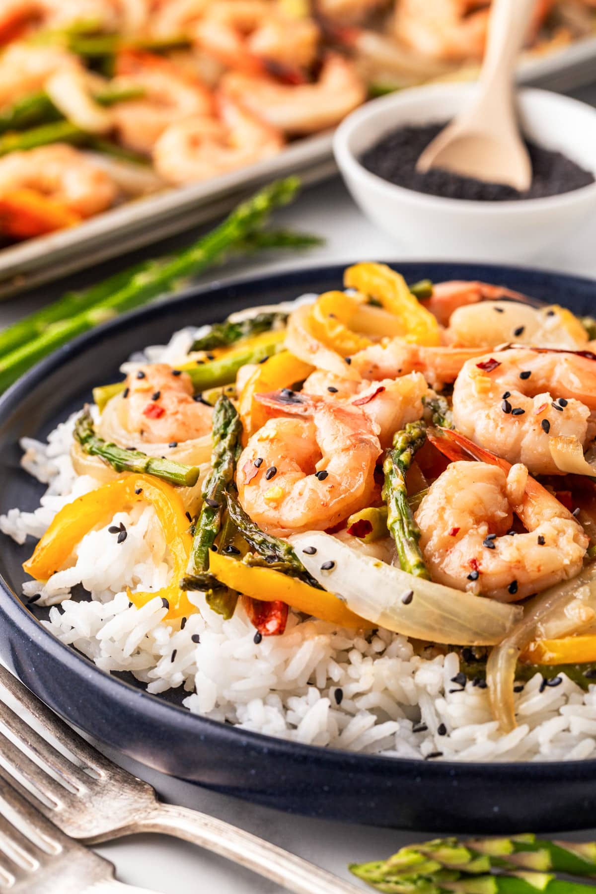 This awesome Shrimp Stir Fry Recipe - Easy Oven Method will have you grabbing the sheet pan again and again. The stir fry sauce with honey, garlic, ginger and more will be what you fall in love with. Shrimp Stir Fry over rice on a plate.