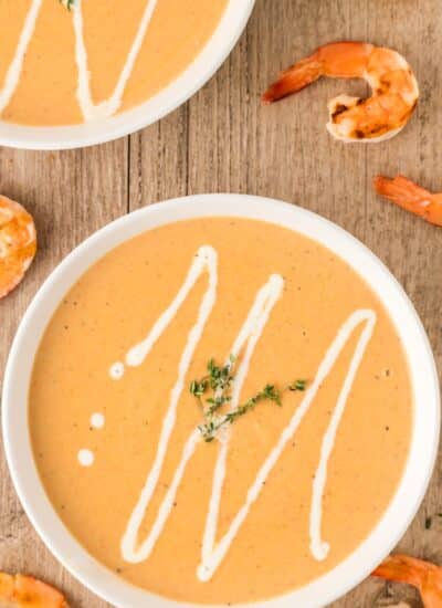 Overhead showing bowls of shrimp bisque with cream drizzled on top.