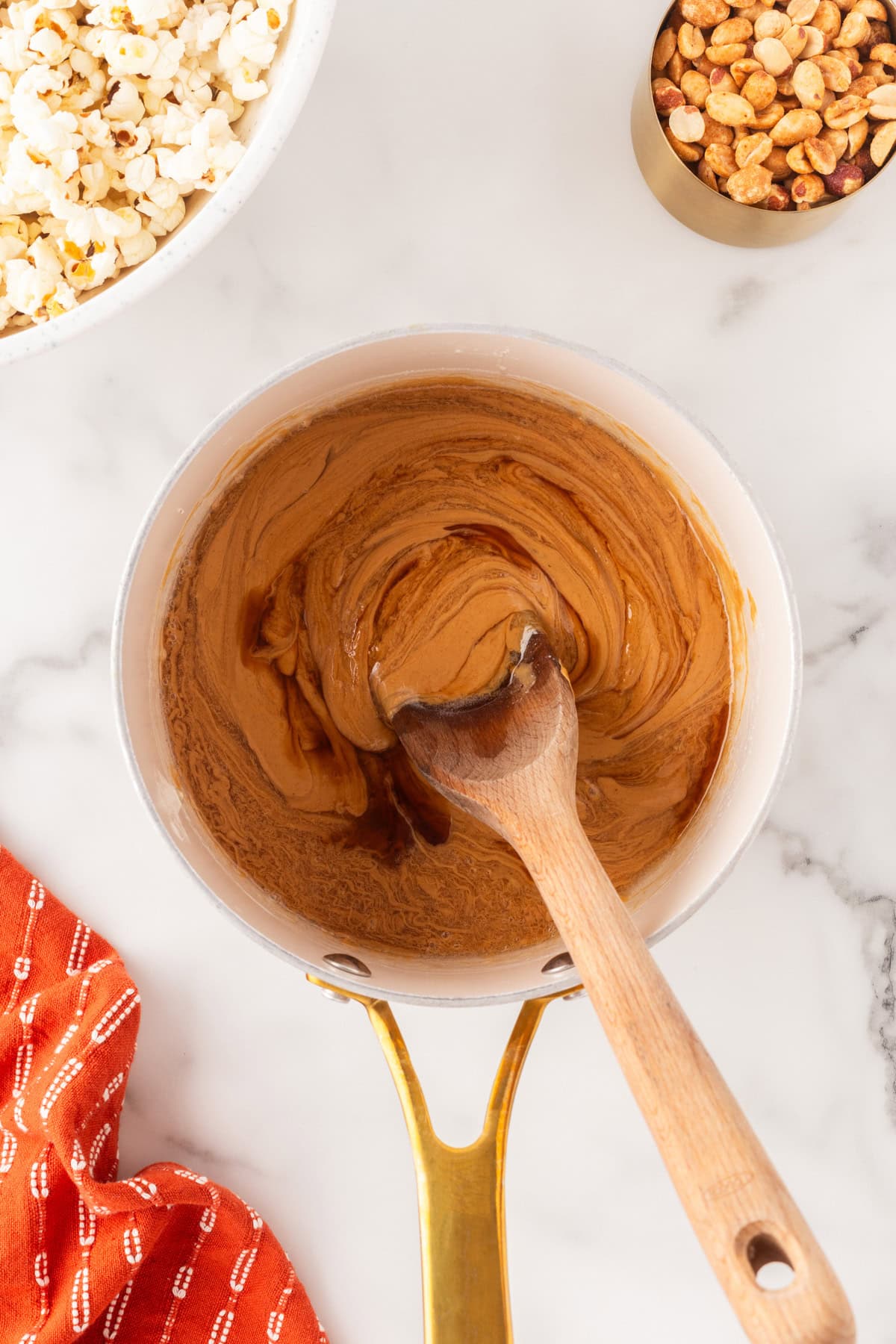 These Popcorn Balls with Peanuts make for a great fall treat for Halloween or for the holidays like Thanksgiving and Christmas. A great portable snack that everyone will love. Mixing the peanut butter mixture.